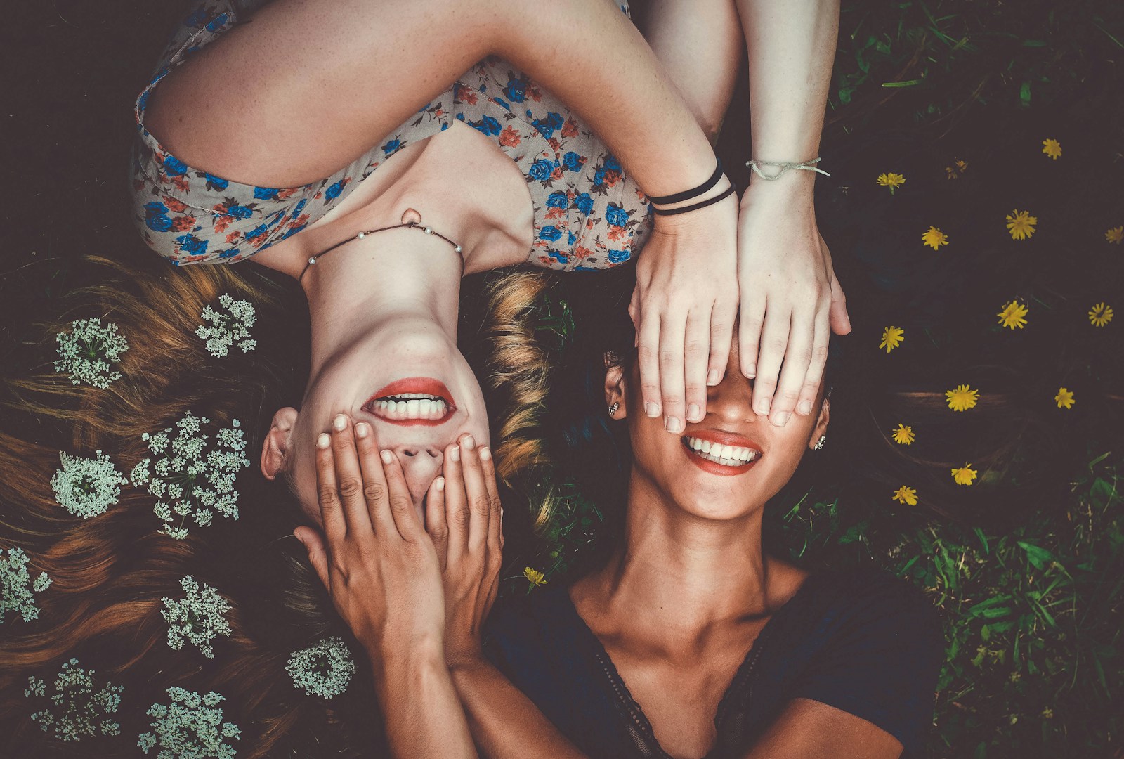 Photo by Sam McNamara man and woman smiling while laying on lawn field