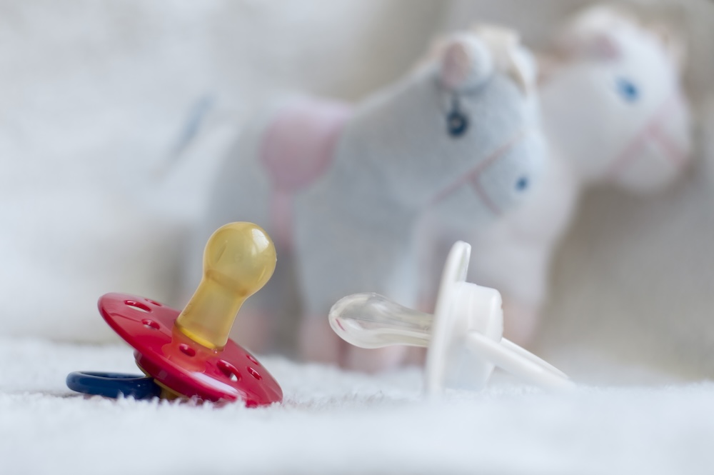 Baby,Pacifiers,Different,Forms,On,A,Background,Of,Toys man and woman smiling while laying on lawn field